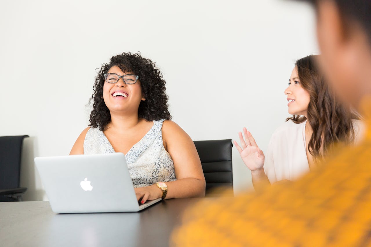 Professional women engaged in a lively meeting at the office using technology.